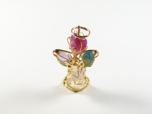 Złoty aniołek z kolorowymi skrzydłami i różową głową na białym tle.