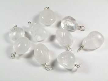 Osiem przezroczystych kamieni z metalowymi zawieszkami leży na białym tle.