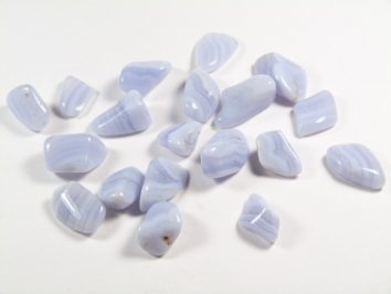 Kilka polerowanych, jasnoniebieskich kamieni leży na białym tle.