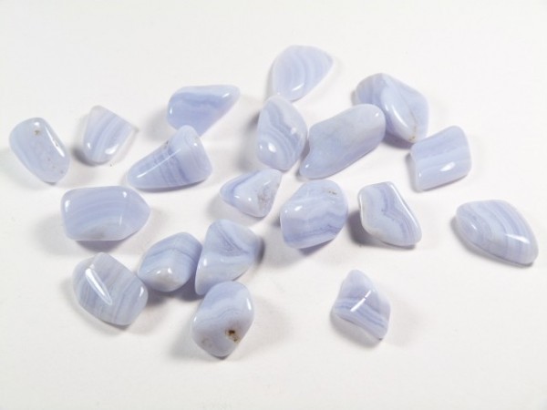 Kilka polerowanych, jasnoniebieskich kamieni leży na białym tle.