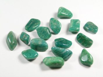 Kilka zielonych, oszlifowanych kamieni leży na białym tle.