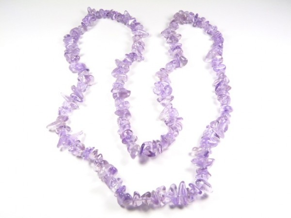 Naszyjnik z fioletowych, nieregularnych koralików z ametystu na białym tle.
