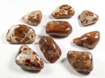 Wypolerowane, brązowo-białe kamienie leżące na białym tle.
