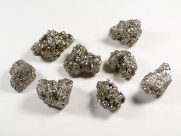Osiem błyszczących grudek pirytu na białym tle.