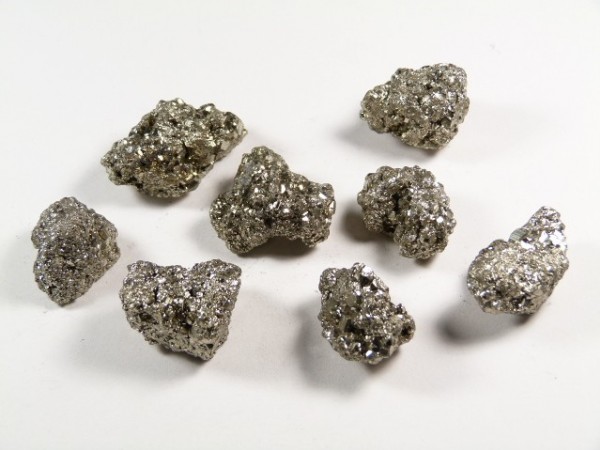 Osiem błyszczących grudek pirytu na białym tle.