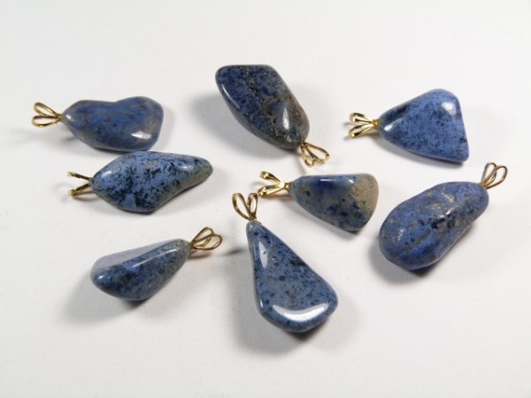 Osiem niebieskich kamieni z zawieszkami, ułożonych na białym tle.
