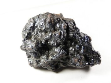 Hematyt - kamień naturalny, surowy, nieszlifowany. Czarny, błyszczący okaz minerału hematytu na białym tle.