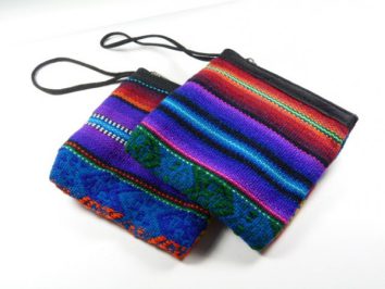 Dwie kolorowe torebki materiałowe z wzorami etnicznymi leżą obok siebie na białym tle.