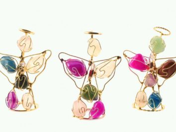 Trzy ozdobne aniołki z drutu i kolorowych kamieni na białym tle.