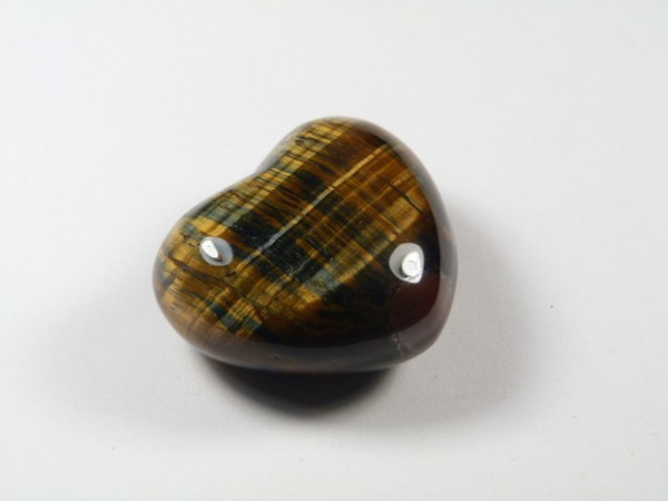 Serce z polerowanego tygrysiego oka na białym tle.