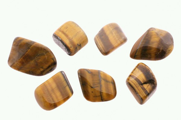 Siedem oszlifowanych kamieni tygrysiego oka na białym tle.