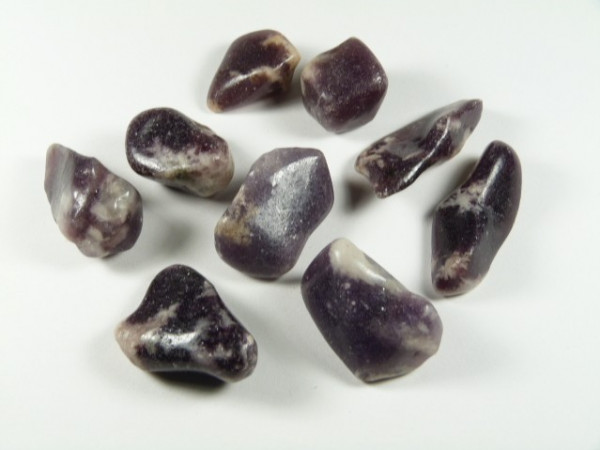 Osiem fioletowo-białych, gładkich kamieni leży na białym tle.