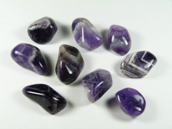 Polerowane kamienie ametystu ułożone na białym tle.