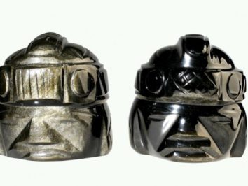 Dwa kamienne popiersia z rzeźbionymi wzorami inspirowane starożytną kulturą prekolumbijską.