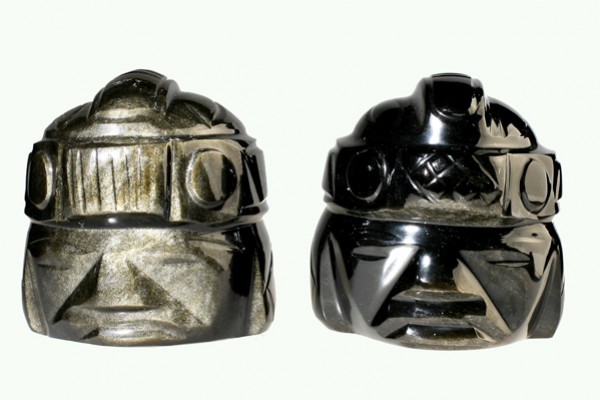 Dwa kamienne popiersia z rzeźbionymi wzorami inspirowane starożytną kulturą prekolumbijską.