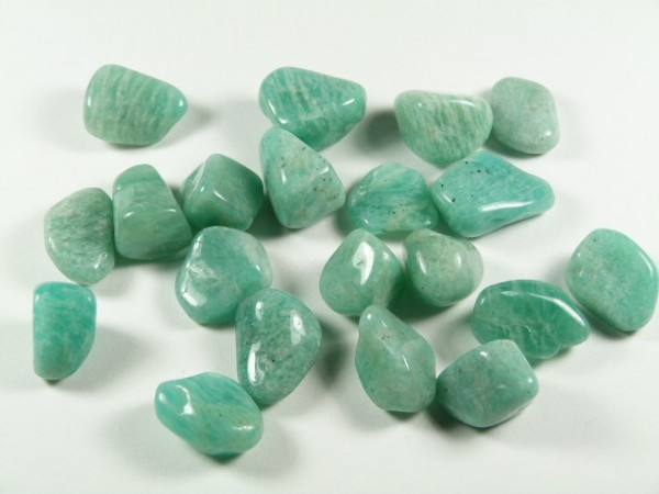 Kilka zielonych, wygładzonych kamieni leży na białym tle.