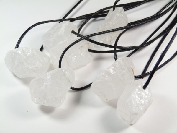 Surowe kryształy kwarcu na czarnych sznurkach, przygotowane do noszenia jako naszyjniki.