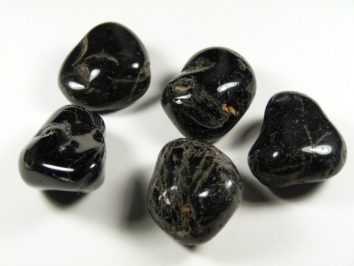 Pięć czarnych, wypolerowanych kamieni leży na białym tle.