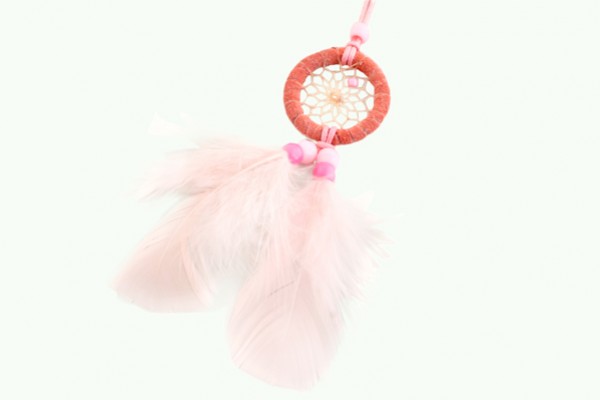 Różowy łapacz snów z piórami i koralikami na jasnym tle.