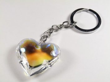 Brelok z przezroczystym sercem, metalowy łańcuszek na białym tle.