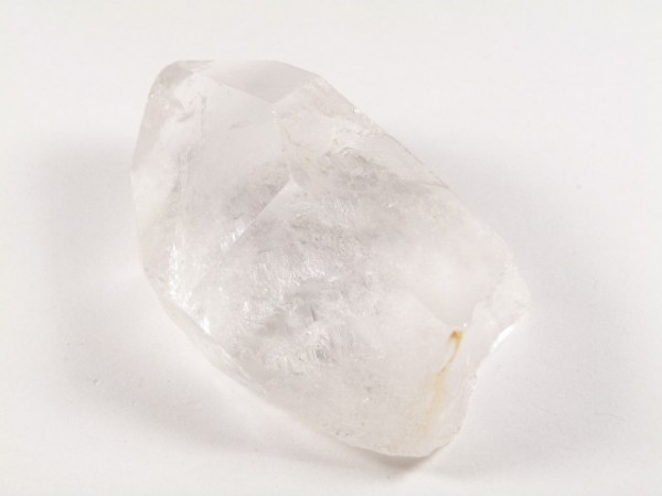 Przezroczysty kryształ kwarcu leży na białym tle.