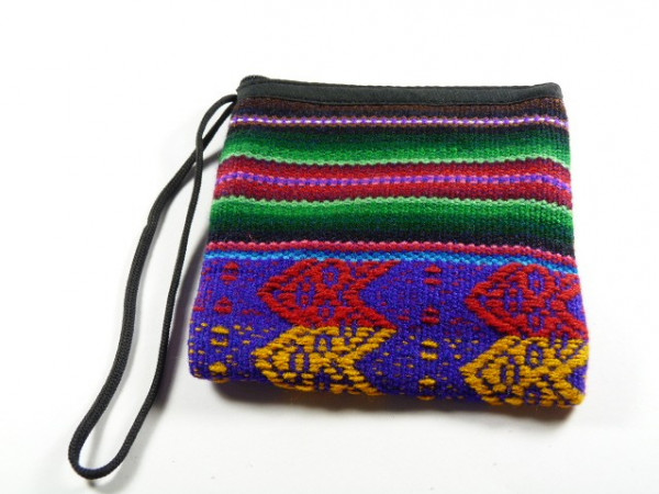 Mała torebka z kolorowym, etnicznym wzorem i czarną rączką na tle białym.