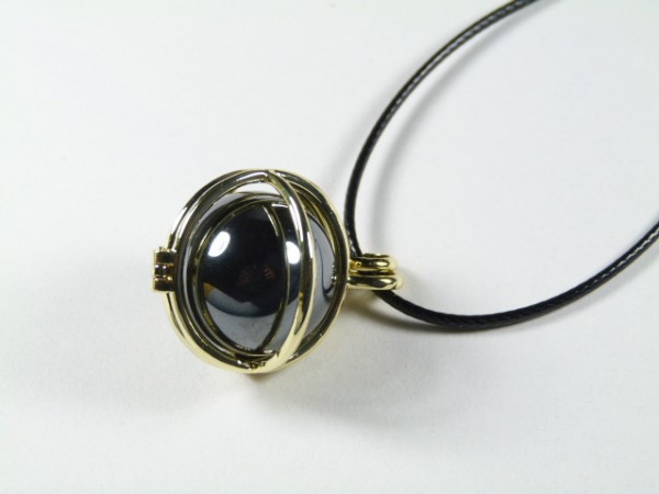 Złoty naszyjnik z czarnym, błyszczącym kamieniem na czarnym sznurku.