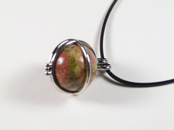 Wisiorek z kolorowym kamieniem w metalowej oprawie na czarnym sznurku.