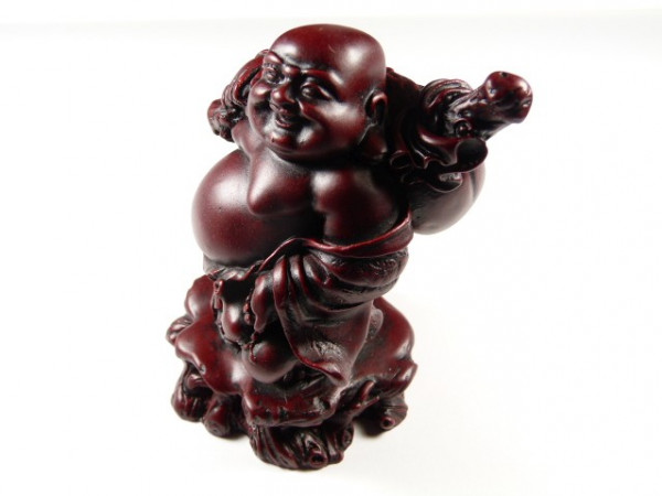 Ciemnoczerwona figurka uśmiechniętego Buddy stojącego z workiem na ramieniu.