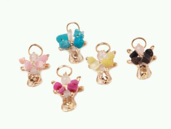 Pięć kolorowych zawieszek aniołków z koralikami ułożonych na białym tle.