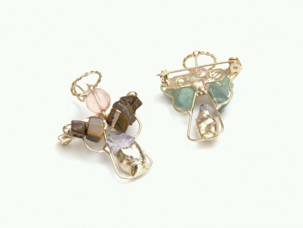 Dwa anioły z drutu i kolorowych kamieni, wykonane jako ozdobne broszki na białym tle.