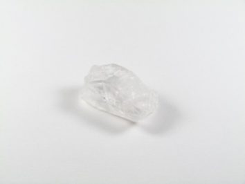 Przezroczysty kryształ kwarcu leży na białym tle.