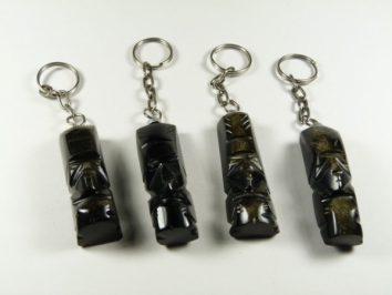 Cztery breloczki z figurkami moai ustawione w rzędzie na białym tle.