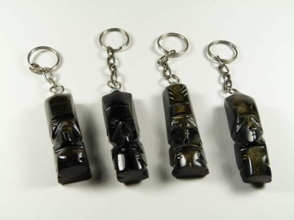 Cztery breloczki z figurkami moai ustawione w rzędzie na białym tle.