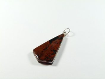 Brązowy wisiorek z kamienia o geometrycznym kształcie na białym tle.