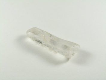 Przezroczysty kryształ kwarcu leżący na białym tle.