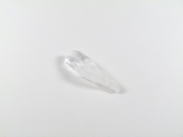 Przezroczysty kryształ kwarcu leży na białym tle.