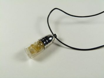 Buteleczka fluoryt żółty - wisiorek. Wisiorek na czarnym sznurku z przezroczystą kapsułką wypełnioną żółtymi kamieniami.