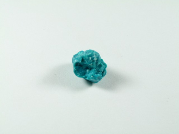 Chryzokola. Niebieski kamień mineralny leży na białym tle.