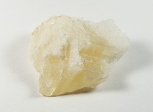 Kalcyt skrzydło anioła - kamień naturalny, surowy, nieszlifowany. Jasnożółty kryształ minerału na białym tle.