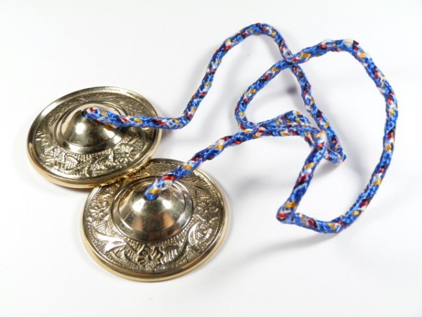 Dwie małe talerzyki perkusyjne połączone kolorowym sznurkiem, leżące na białym tle.