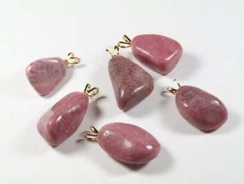Sześć różowych kamieni z zawieszkami na białym tle, gotowych do noszenia jako biżuteria.