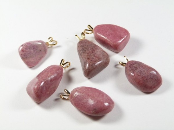 Sześć różowych kamieni z zawieszkami na białym tle, gotowych do noszenia jako biżuteria.
