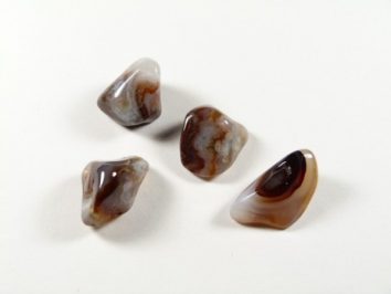 Cztery wypolerowane kamienie agatowe leżą na białym tle.