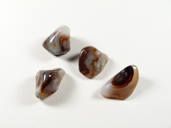 Cztery wypolerowane kamienie agatowe leżą na białym tle.