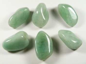 Sześć zielonych, oszlifowanych kamieni ułożonych na białym tle.