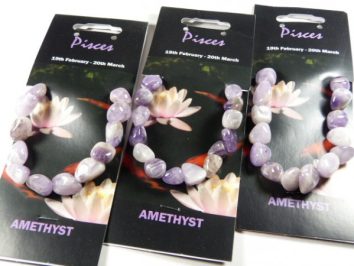 Trzy bransoletki z ametystu na czarnych kartonikach z napisem „Pisces” i „Amethyst”.