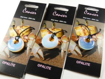 Trzy zawieszki z opalitu na sznurku, z motywem znaku zodiaku Rak na tle kraba.