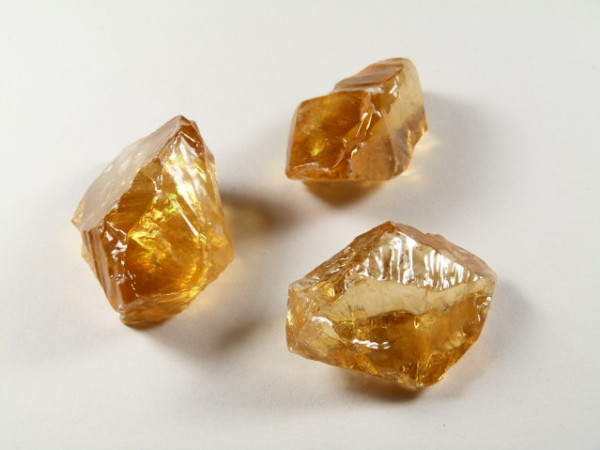 Trzy surowe kryształy cytrynu na białym tle.