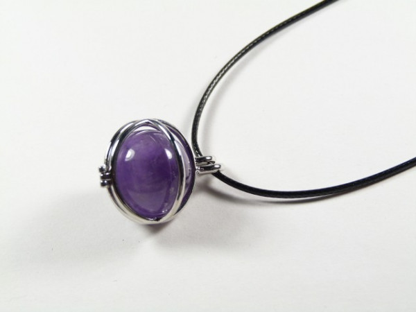 Wisiorek z fioletowym kamieniem na czarnym rzemyku, widok z góry.